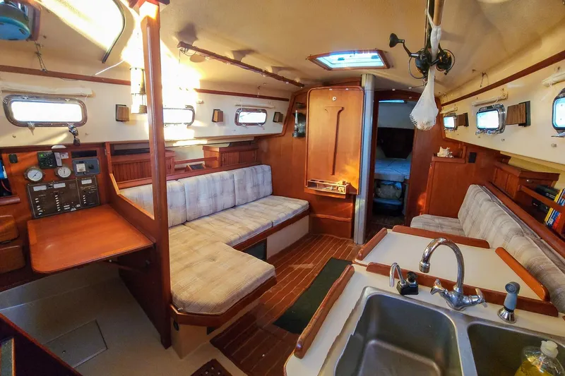 Slide: The Image of Interior of a 1990 Island Packet 32 sailboat with cozy seating and wooden finishes. - 23