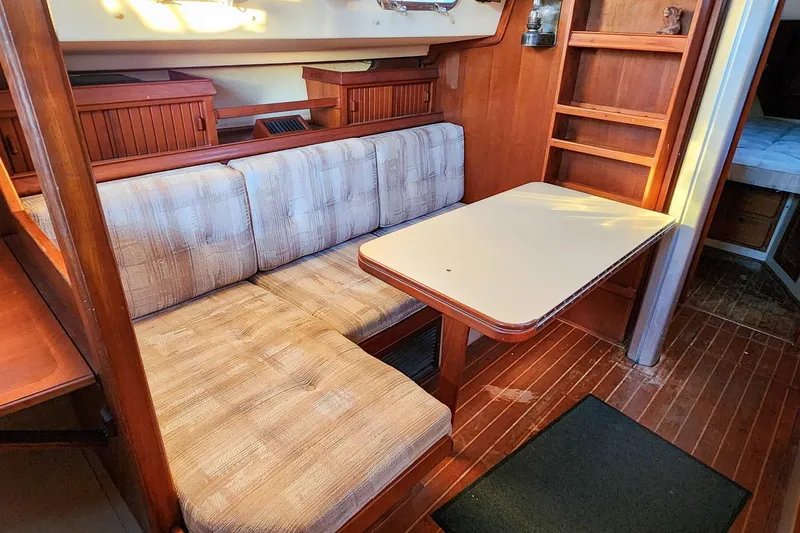Slide: The Image of Cozy interior of a 1990 Island Packet 32 sailboat with cushioned seating and wooden table. - 31