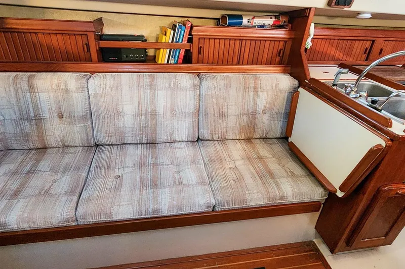 Slide: The Image of Interior of 1990 Island Packet 32 sailboat with cushioned seating and wooden cabinetry. - 33