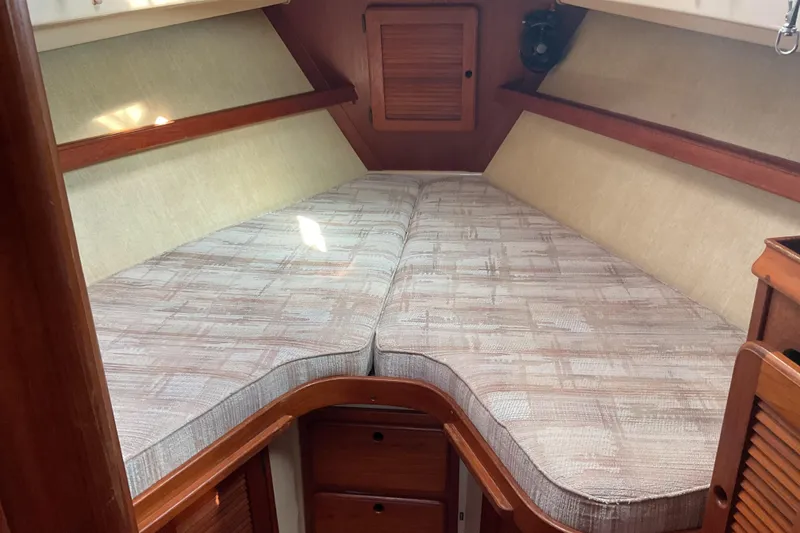 Slide: The Image of 1990 Island Packet 32 sailboat interior with cozy V-berth and wooden cabinetry. - 34