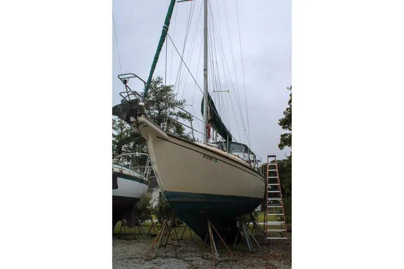 Slide: The Image of 1990 Island Packet 32 sailboat on land with ladder and trees in background. - 4