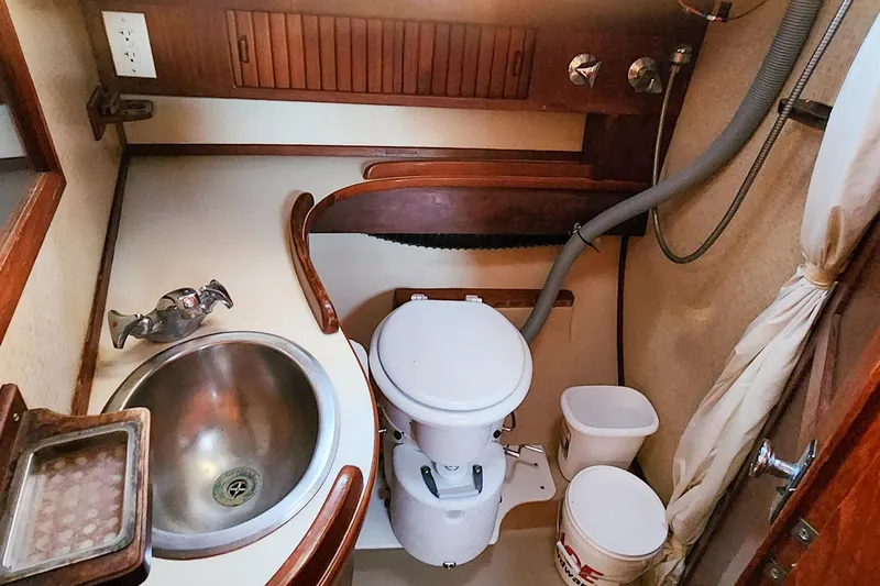 Slide: The Image of 1990 Island Packet 32 sailboat bathroom with sink, toilet, and wooden cabinetry. - 41