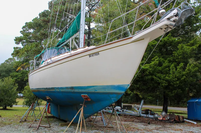 Slide: The Image of 1990 Island Packet 32 sailboat on stands, surrounded by trees. - 49