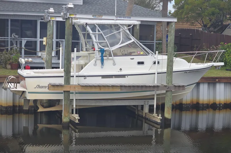 The Image of White 2001 Shamrock 26 boat on a lift, docked near a waterfront home. - 0