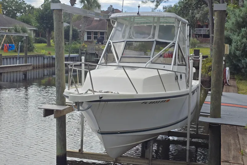 Slide: The Image of White 2001 Shamrock 26 boat docked on a lift in a residential canal. - 1