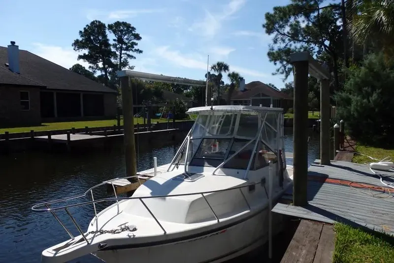 Slide: The Image of 2001 Shamrock 26 boat docked by a canal, surrounded by trees and houses. - 18