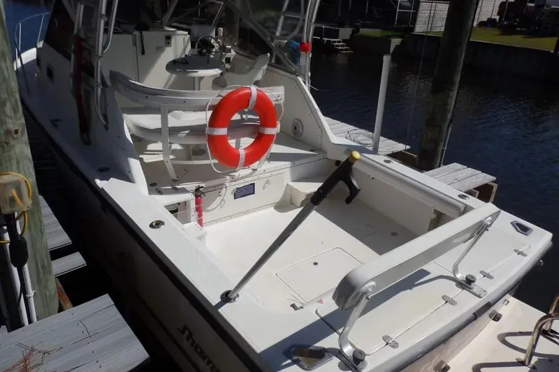 Slide: The Image of 2001 Shamrock 26 boat docked, featuring a life preserver and fishing equipment. - 2