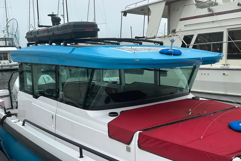 Slide: The Image of 2023 Axopar Brabus boat with blue roof and red cover docked at marina. - 8