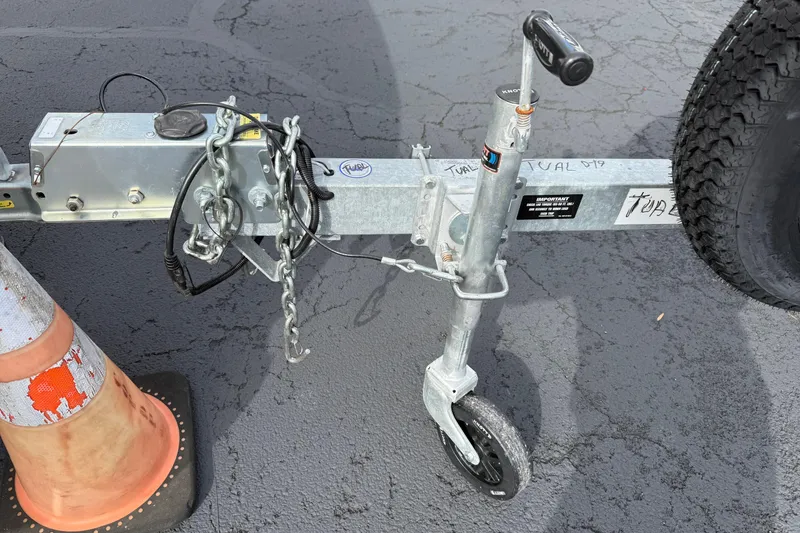 Slide: The Image of Trailer hitch and wheel assembly of a 2023 Qwest RLS 822 on asphalt. - 2