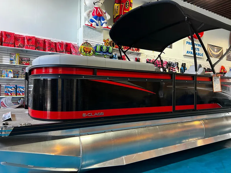 Slide: The Image of 2023 Qwest RLS 822 pontoon boat with red and black design in showroom. - 4