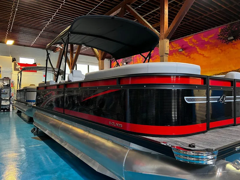 Slide: The Image of 2023 Qwest RLS 822 pontoon boat with sleek red and black design in showroom. - 6