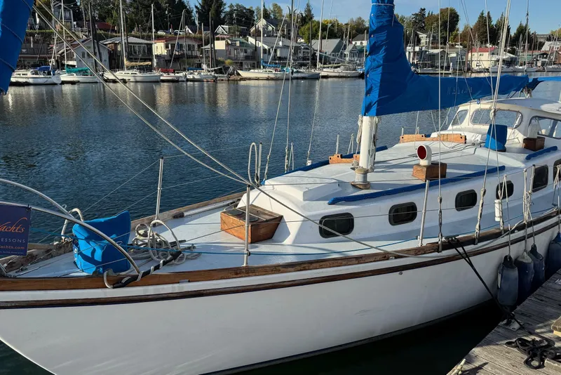 The Image of 1975 Cascade 36 sailboat docked in a marina, featuring blue sails and a white hull. - 0