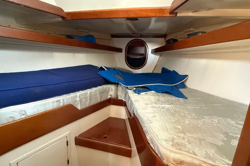 Slide: The Image of Interior cabin of a 1975 Cascade 36 sailboat with wooden shelves and blue cushions. - 15