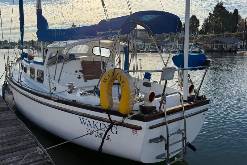 Slide: The Image of 1975 Cascade 36 sailboat docked, featuring blue canopy and yellow life preserver, in a serene marina. - 21