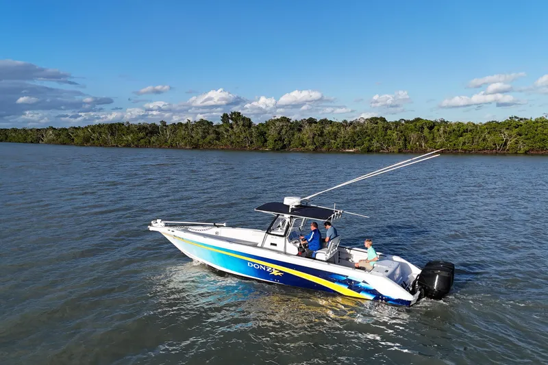 Slide: The Image of 2000 Donzi 35 boat cruising on a scenic river with lush green shoreline. - 2