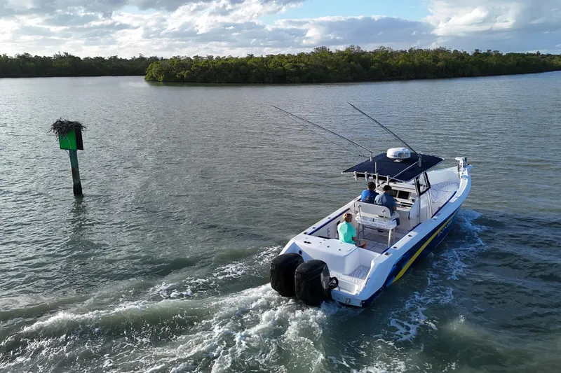 Slide: The Image of 2000 Donzi 35 boat cruising on a calm river with lush greenery. - 24