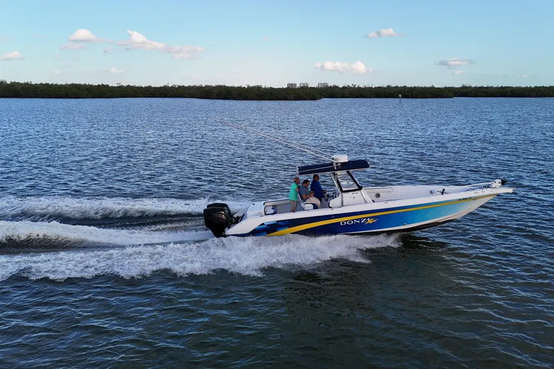 Slide: The Image of 2000 Donzi 35 boat cruising on open water under a clear blue sky. - 36
