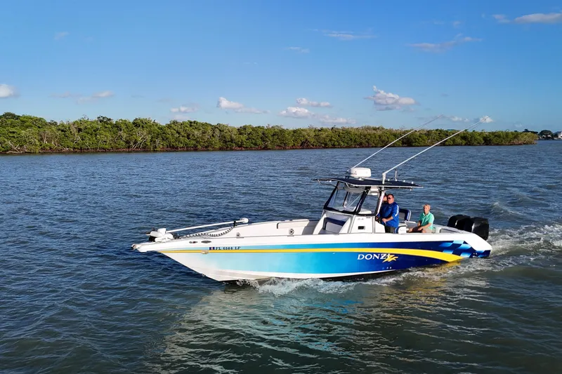 The Image of 2000 Donzi 35 boat cruising on a scenic waterway with lush greenery in the background. - 0