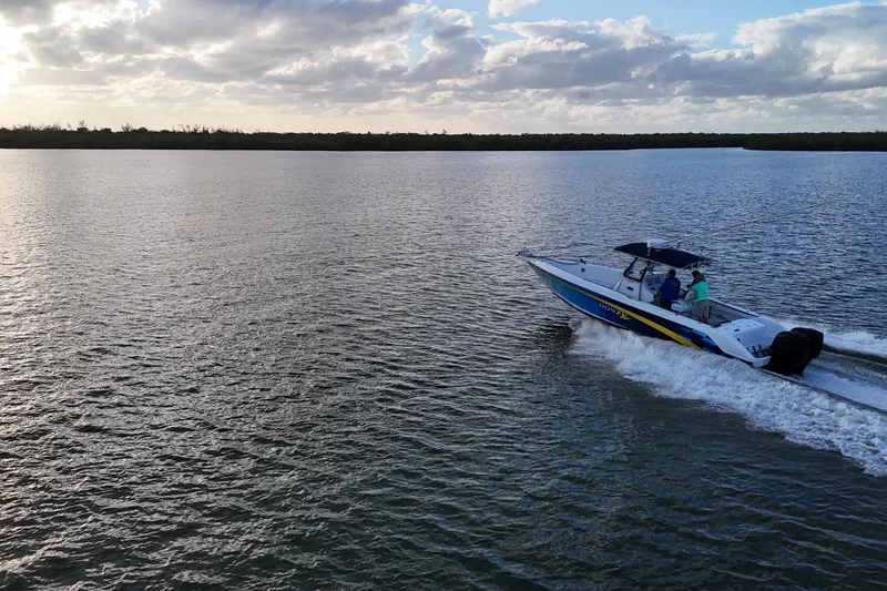 Slide: The Image of 2000 Donzi 35 boat cruising on a serene lake under a cloudy sky. - 27