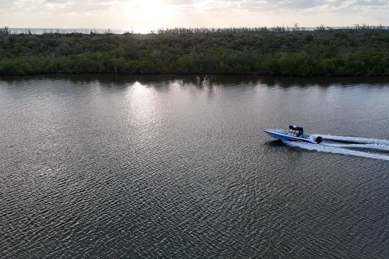 Slide: The Image of A 2000 Donzi 35 speedboat cruising on a serene river at sunset. - 33