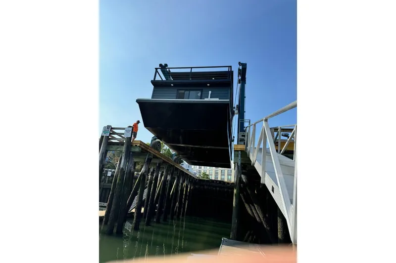 Slide: The Image of Modern 2026 East Coast Houseboat Bayview being lifted at a dock under clear blue sky. - 10
