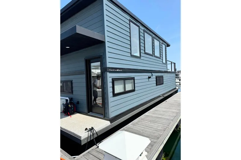 Slide: The Image of Modern 2026 East Coast Houseboat Bayview docked, featuring sleek blue exterior and large windows. - 12