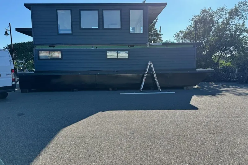 Slide: The Image of Houseboat on trailer, East Coast Houseboat Bayview 2026 model, parked outdoors with ladder. - 5