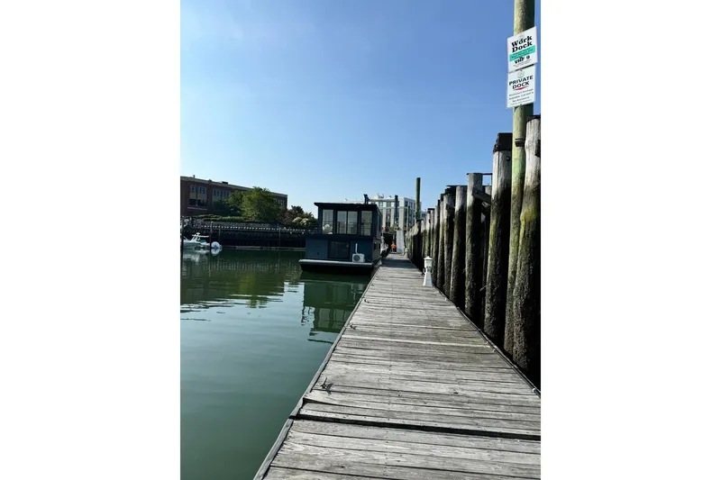 Slide: The Image of Docked East Coast Houseboat Bayview 2026 under clear blue sky. - 8