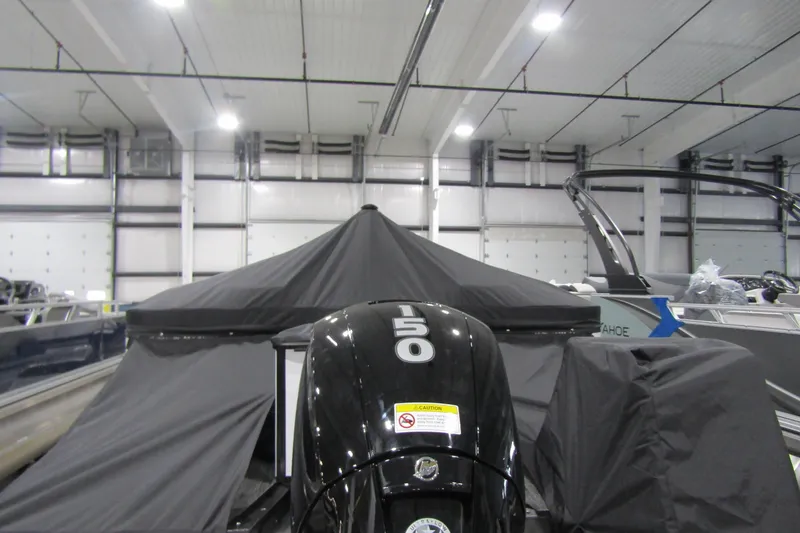 Slide: The Image of 2025 Avalon LSZ Quad Lounger boat with 150 HP engine in indoor storage. - 13