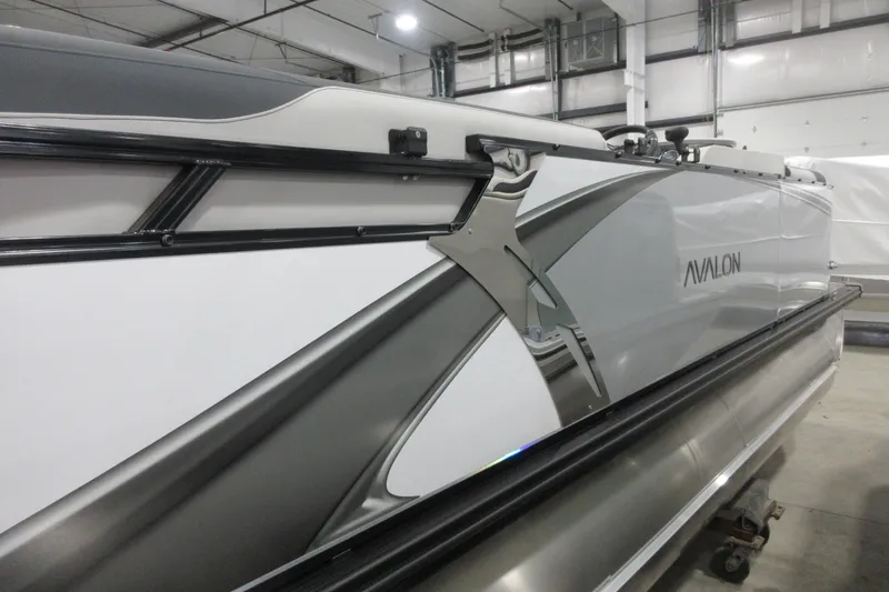 Slide: The Image of 2025 Avalon LSZ Quad Lounger pontoon boat in a showroom setting. - 2