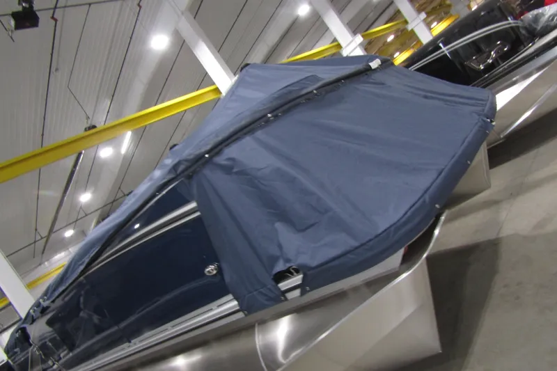 Slide: The Image of 2026 Avalon LSZ Quad Lounger boat covered in blue tarp, displayed indoors. - 13