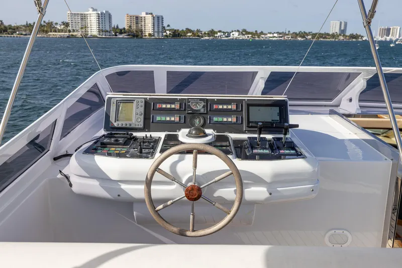 Slide: The Image of Helm of 1999 Azimut 100 Jumbo yacht with navigation controls, overlooking ocean and cityscape. - 16