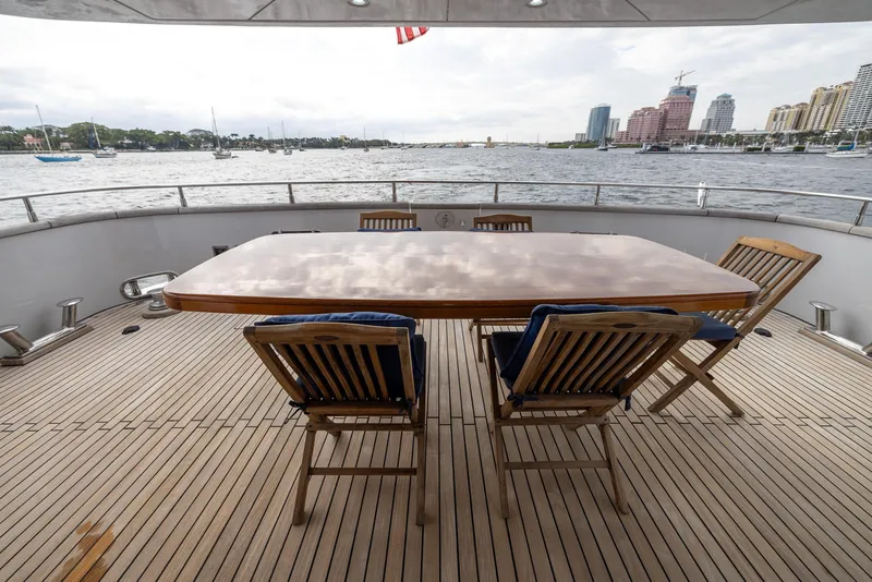 Slide: The Image of Deck view of 1999 Azimut 100 Jumbo yacht with wooden table and chairs, overlooking waterfront. - 27