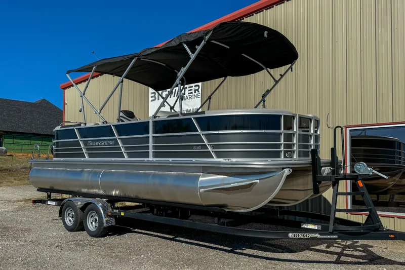 Slide: The Image of 2024 Berkshire 24RFX LE pontoon boat on trailer, parked outside a beige building. - 6