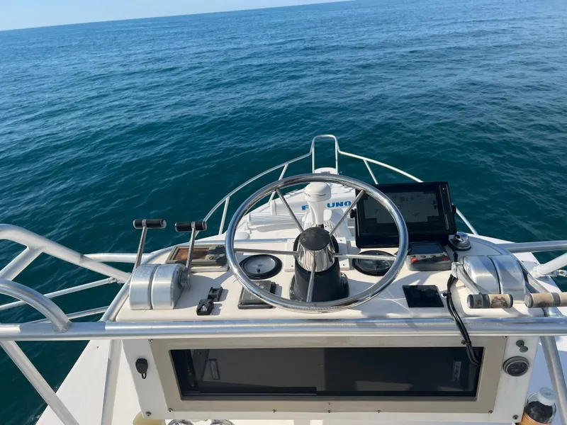 Slide: The Image of 1998 Albemarle 320 Express Fisherman helm with ocean view, featuring steering wheel and controls. - 13