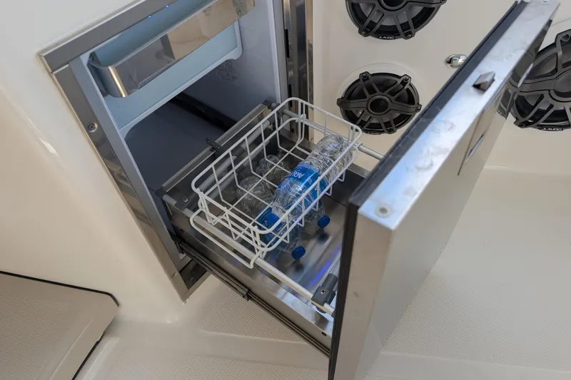 Slide: The Image of Open cooler drawer on 2024 Boston Whaler 350 Realm, with water bottles inside. - 11