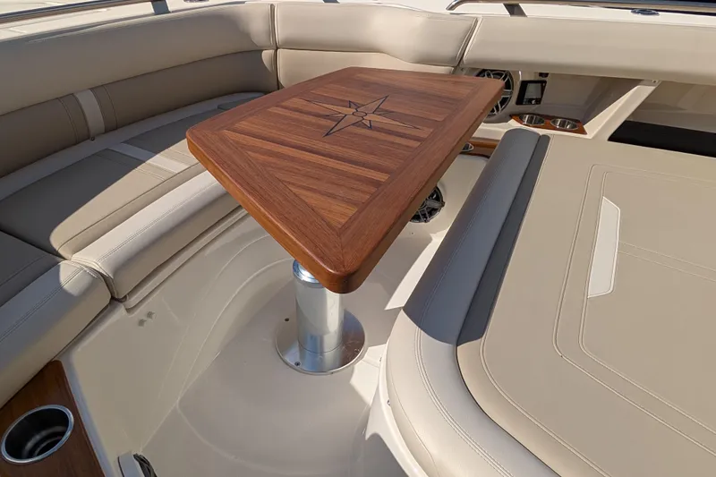 Slide: The Image of 2024 Boston Whaler 350 Realm interior with elegant wood table and beige seating. - 15
