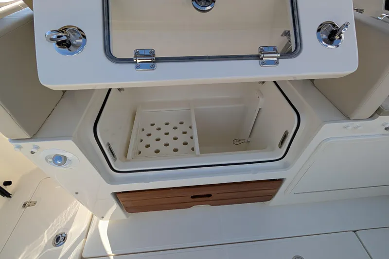 Slide: The Image of 2024 Boston Whaler 350 Realm boat storage compartment with open hatch and drainage system. - 21