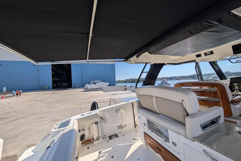 Slide: The Image of 2024 Boston Whaler 350 Realm interior view at marina with blue warehouse background. - 24