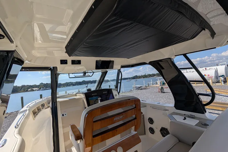 Slide: The Image of 2024 Boston Whaler 350 Realm interior with helm view, dockside, under sunny skies. - 29