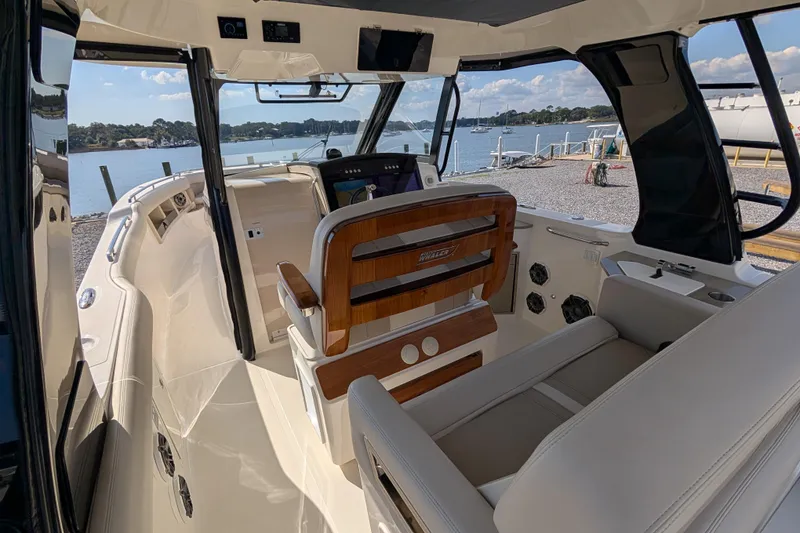 Slide: The Image of 2024 Boston Whaler 350 Realm interior with helm, luxurious seating, and waterfront view. - 3