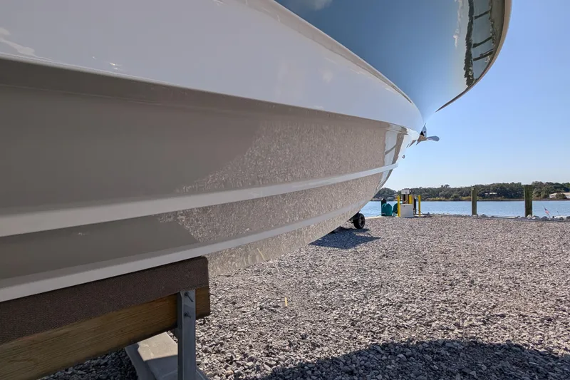 Slide: The Image of 2024 Boston Whaler 350 Realm boat hull on gravel near water. - 36