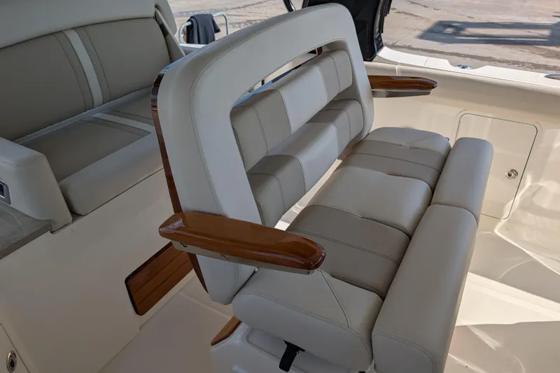 Slide: The Image of Luxury seating on 2024 Boston Whaler 350 Realm boat, featuring plush cushions and wooden armrests. - 4
