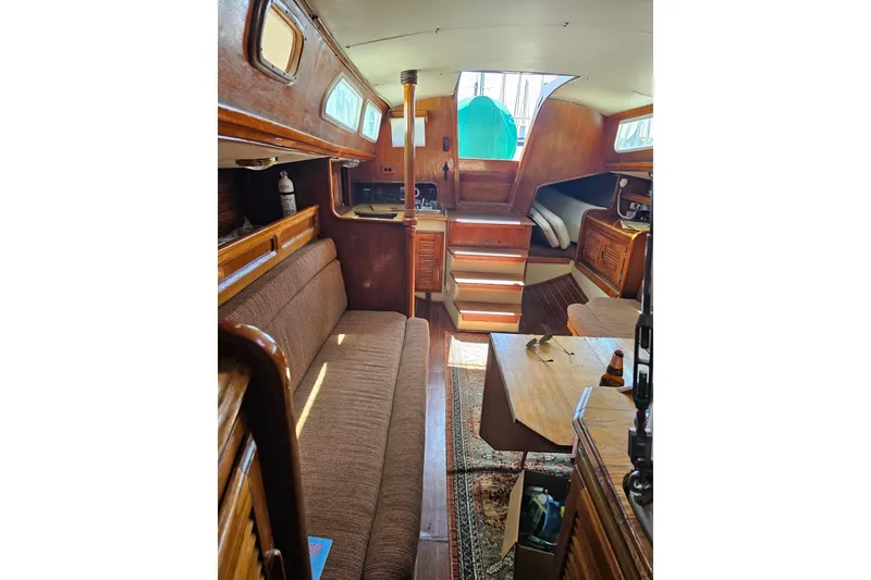 Slide: The Image of Interior of a 1978 Islander 36 sailboat, featuring wooden furnishings and cozy seating. - 13