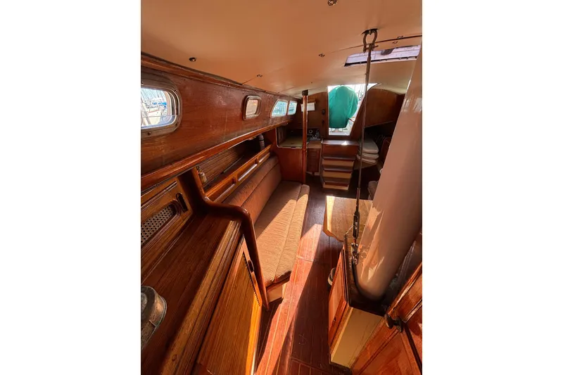 Slide: The Image of 1978 Islander 36 sailboat interior with wooden finish and cozy seating area. - 15