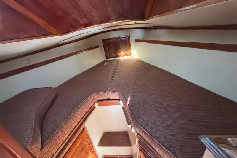 Slide: The Image of 1978 Islander 36 sailboat interior cabin with cozy brown cushions and wooden accents. - 18