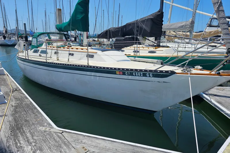 Slide: The Image of 1978 Islander 36 sailboat docked in marina, featuring green sail cover. - 3