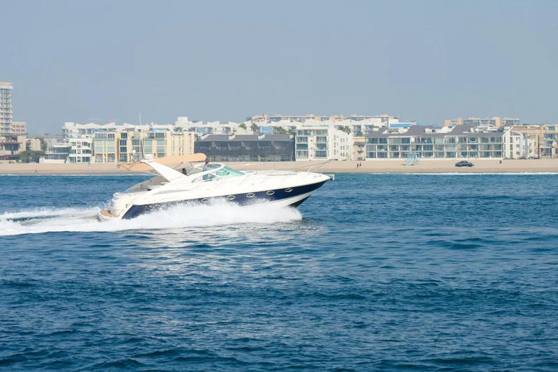 Slide: The Image of 2001 Fairline 43 yacht cruising near a coastal cityscape. - 11