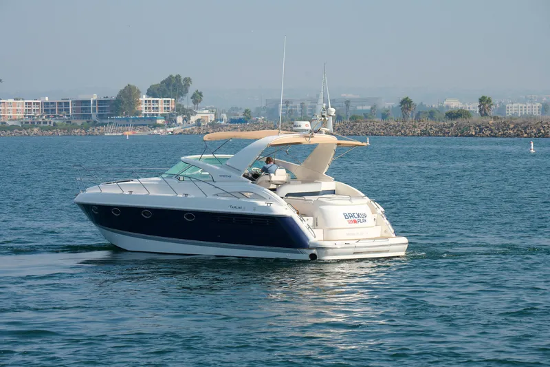 Slide: The Image of 2001 Fairline 43 yacht cruising on calm waters near a coastal cityscape. - 2