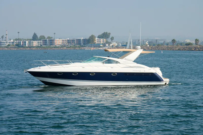 Slide: The Image of 2001 Fairline 43 yacht cruising on calm waters near a coastal cityscape. - 3